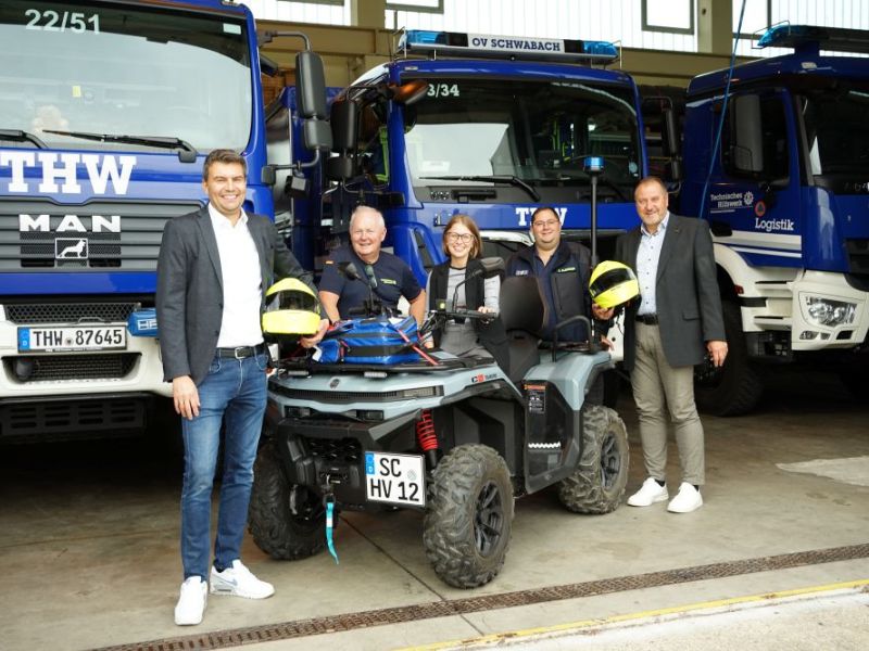 Menschen vor THW Fahrzeugen und Quad